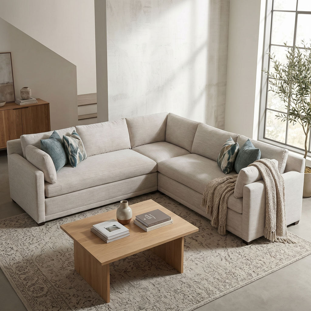 Angled view of Sylvie bench seat sectional in a cozy corner with textured walls and decorative pillows.