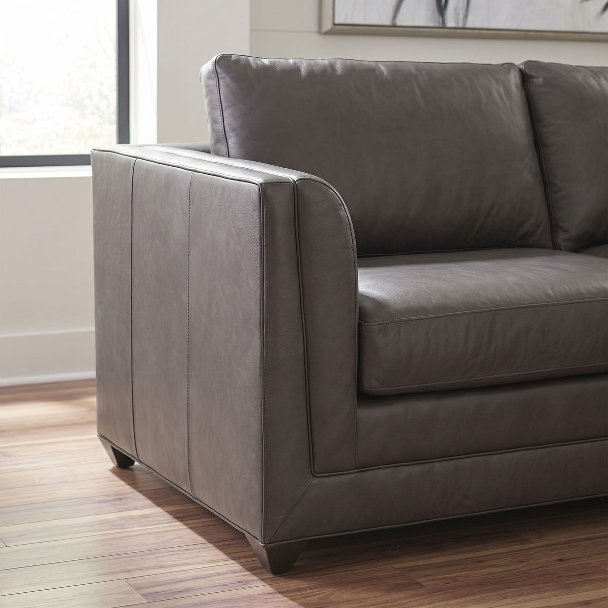 Close-up of Belmont Sectional Sofa's armrest and cushion showing fabric texture, stitching, and plush cushioning on hardwood floor.