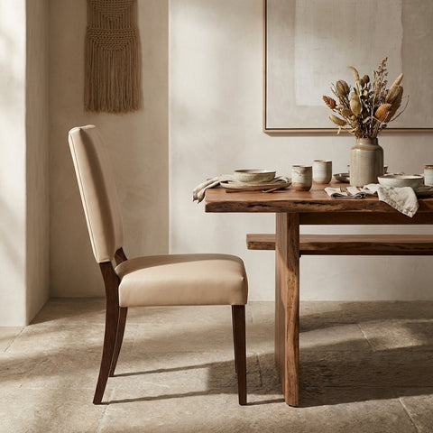Stylized side profile of the ClairLeather Chair at a dining table, emphasizing craftsmanship and natural leather with warm diffuse lighting and minimalist background.