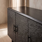 Close-up of the Silvanos Sideboard showing its black lacquered mango wood surface with soft natural light highlighting its smooth, reflective finish.