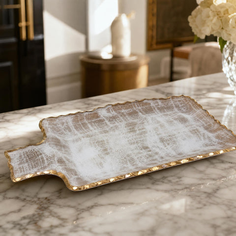 Close-up of luxurious gold brushed tray with intricate border on marble table in a stylish home interior.