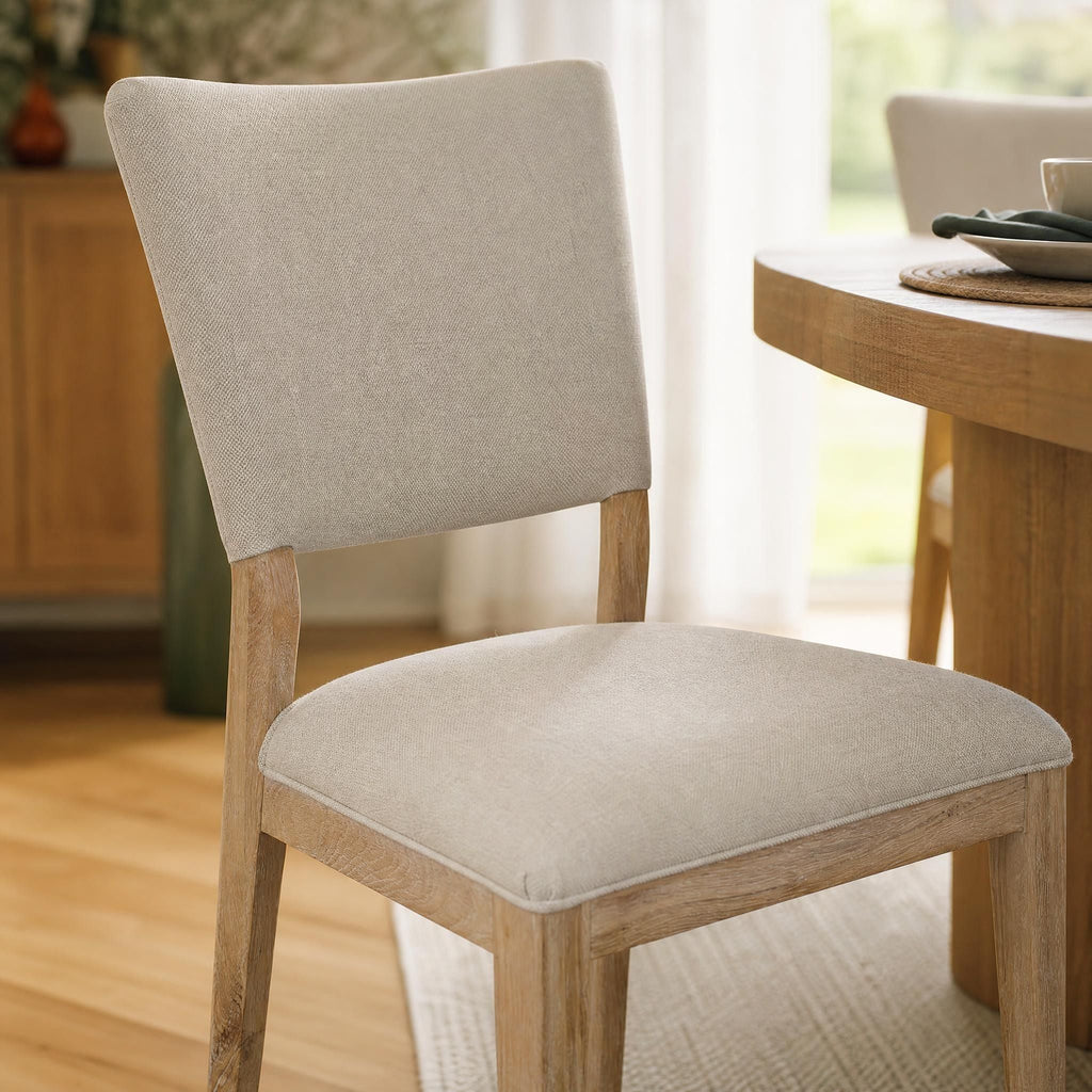 Close-up of Lucile Dining Chair's soft fabric upholstery, stitching details, and oak wood grain in stylish dining area.