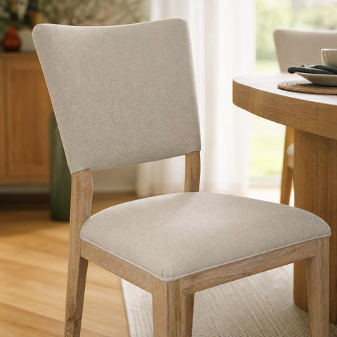 Close-up of Lucile Dining Chair's soft fabric upholstery, stitching details, and oak wood grain in stylish dining area.