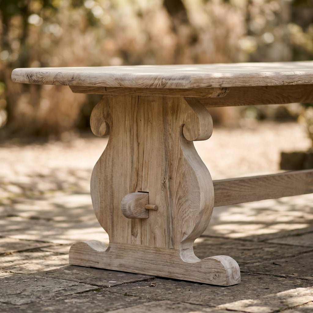 Close-up of weathered teak table surface showing grain and handcrafted details in an outdoor setting.