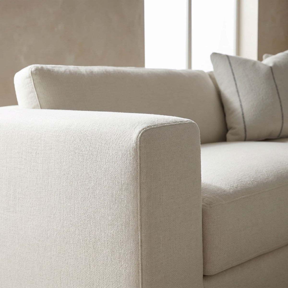 Close-up of Dominic Sectional's fabric upholstery showing fine woven texture and stitching detail under soft natural light.