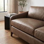 Close-up of the FRANNIE LEATHER SOFA showing detailed stitching and rich leather surface in a modern living room scene.
