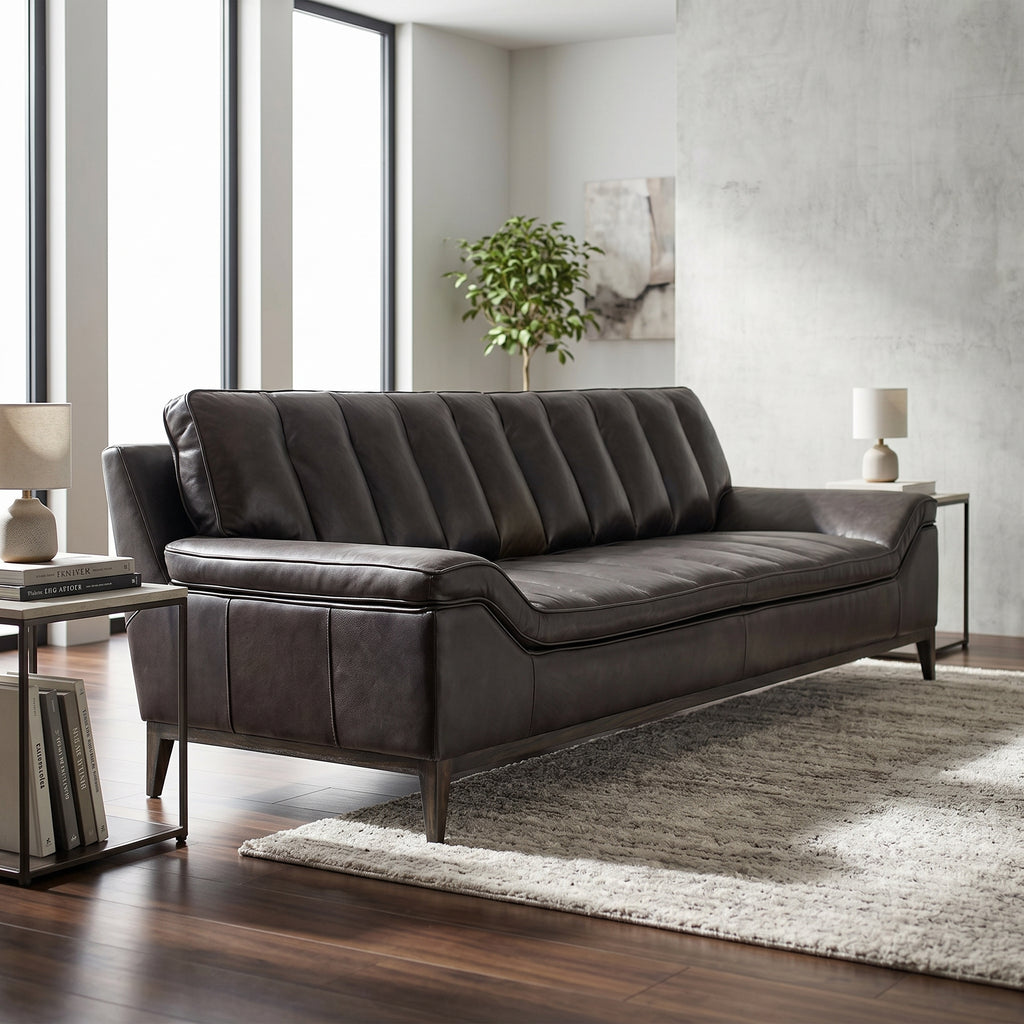 Full view of Kandor Leather Sofa in a contemporary living room highlighting its sleek profile, angular arms, and textured dark leather.