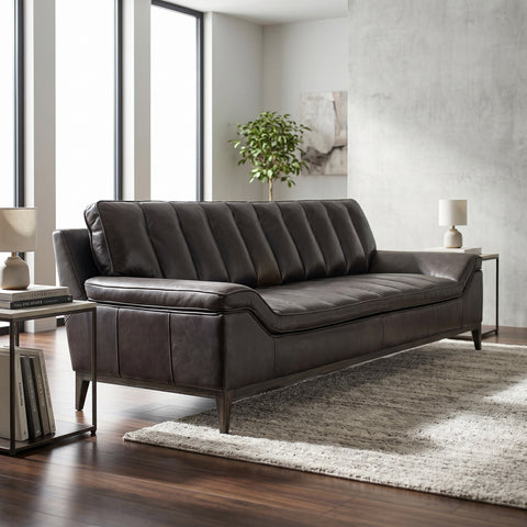 Full view of Kandor Leather Sofa in a contemporary living room highlighting its sleek profile, angular arms, and textured dark leather.