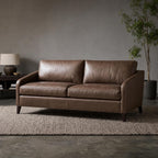 Full view of the Frannie Leather Sofa in a dark gray vintage studio with textured rug and clean lines.
