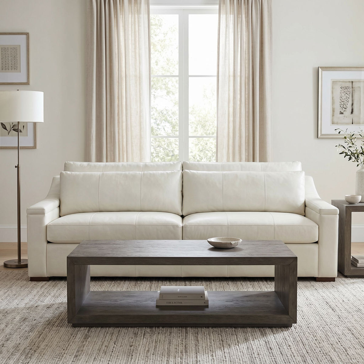 Full perspective of Lowell Sofa in ivory leather with neutral decor in a well-lit living room.