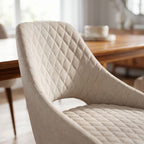 Close-up of Herchel Dining Chair's upholstered seat and backrest highlighting fabric texture and stitch details in an elegant dining setting.