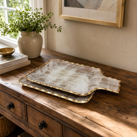 Large gold brushed tray displayed on a rustic wooden sideboard with natural decor in a warmly lit living space.