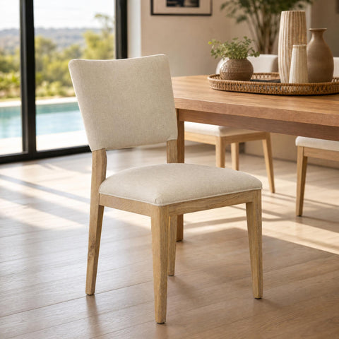 Elegant Lucile Dining Chair with oak frame and light sand upholstery in modern dining setting with natural lighting and wood floor.