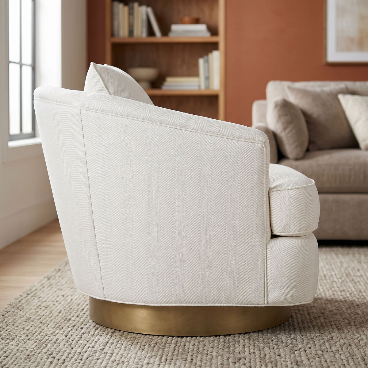 Side profile of Ophelia Swivel Chair on textured rug in a warm, inviting lounge emphasizing craftsmanship and comfortable design.