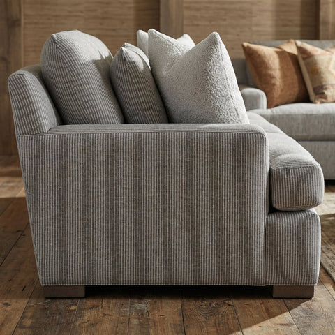 Side profile of the NEST SOFA showing cushions, stitching, and fabric weave in a cozy home interior with warm lighting.