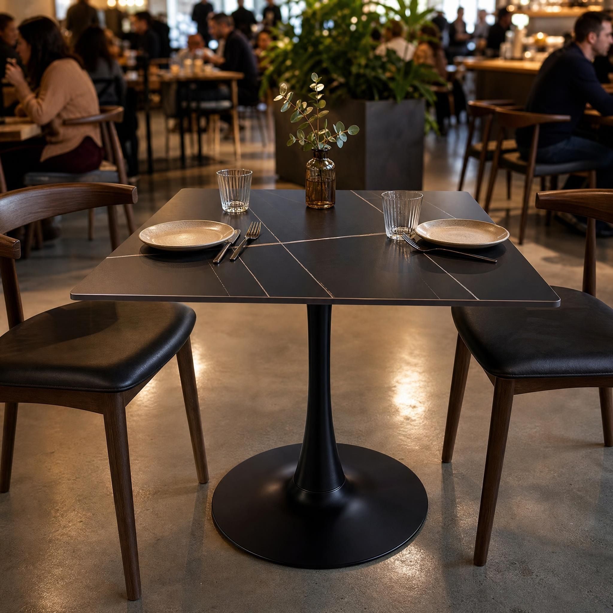 Centered shot of Valli dining table in a lively café with plates and cutlery on durable sintered stone surface.